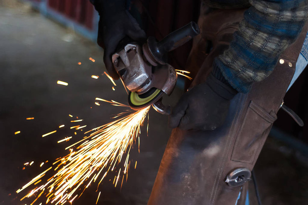 Blacksmith grinding the metal horse shoe peace to shape it. - Photo, Image