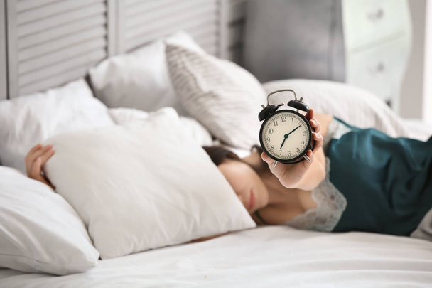 Manhã de mulher bonita com despertador deitado na cama
 - Foto, Imagem
