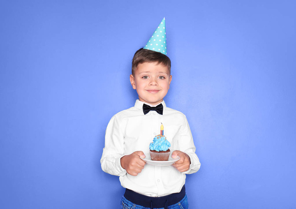 Χαριτωμένο μικρό αγόρι με γενέθλια cupcake σε χρώμα φόντου - Φωτογραφία, εικόνα