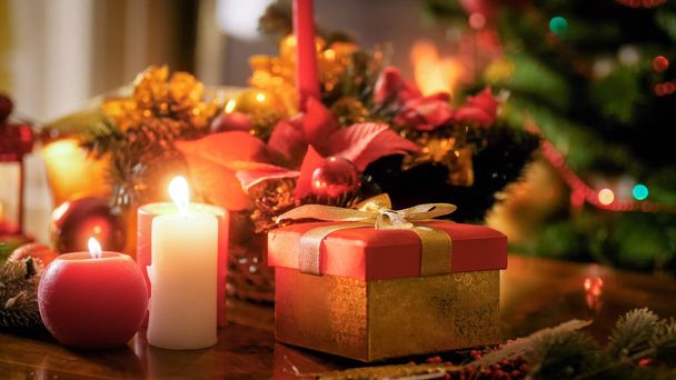Immagine di primo piano di candele accese in piedi contro la scatola regalo e l'albero di Natale
 - Foto, immagini