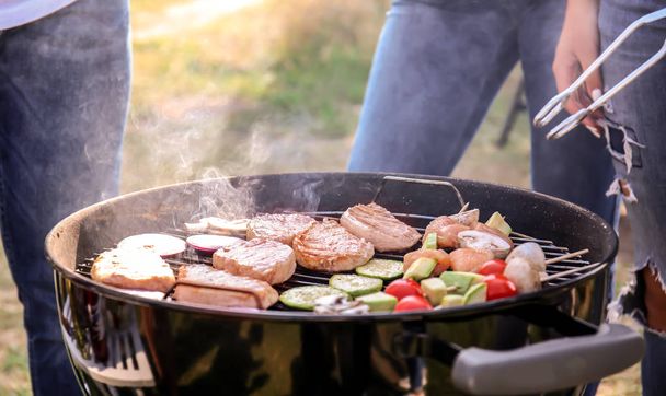 People preparing meat and vegetables on modern grill outdoors - Foto, Imagen