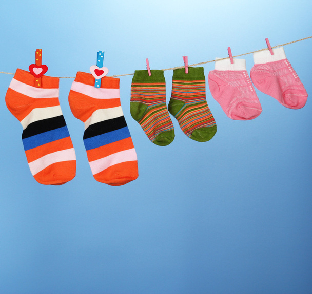 Colorful socks hanging on clothesline, on color background - Fotoğraf, Görsel