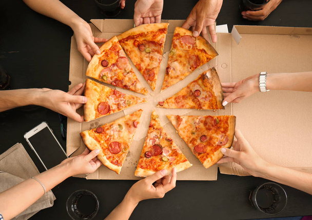 Młodzi ludzie plastrami gorące pysznej pizzy z kartonu - Zdjęcie, obraz