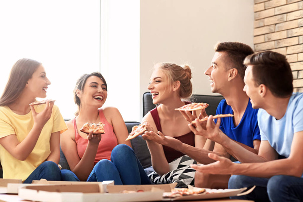Молоді люди розважаються на вечірці зі смачною піцою в приміщенні
 - Фото, зображення