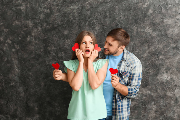 Gelukkige jonge paar met rode harten op grunge achtergrond - Foto, afbeelding