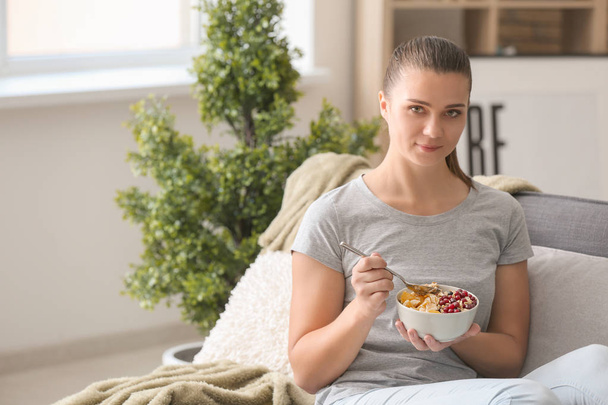 Beautiful young woman eating tasty oatmeal at home - Фото, зображення