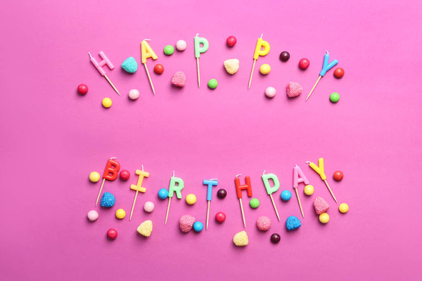 Phrase HAPPY BIRTHDAY made of candles and candies on color background - Foto, imagen