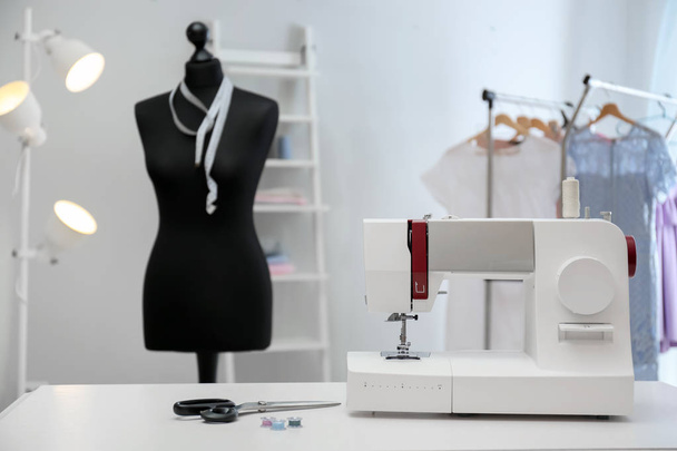 Moderne naaimachine met de kleermaker benodigdheden op tafel in werkplaats - Foto, afbeelding