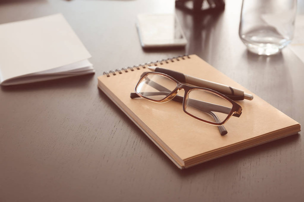Quaderno con occhiali da vista sul tavolo preparato per meeting di lavoro in sala conferenze
 - Foto, immagini