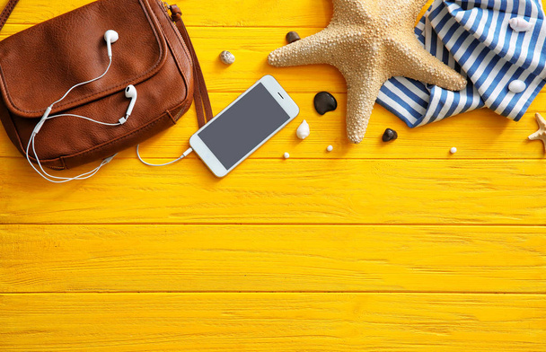 Σύνθεση με smartphone, κομψή τσάντα και αστερία σε έγχρωμο φόντο ξύλινη - Φωτογραφία, εικόνα
