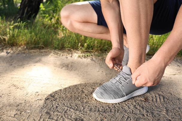 Спортивний чоловік зав'язує шнурки перед бігом у парку
 - Фото, зображення
