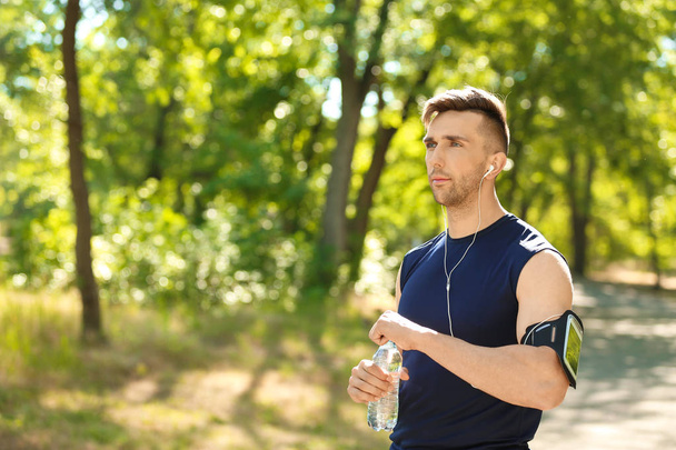 Спортивний чоловік з пляшкою води в парку
 - Фото, зображення