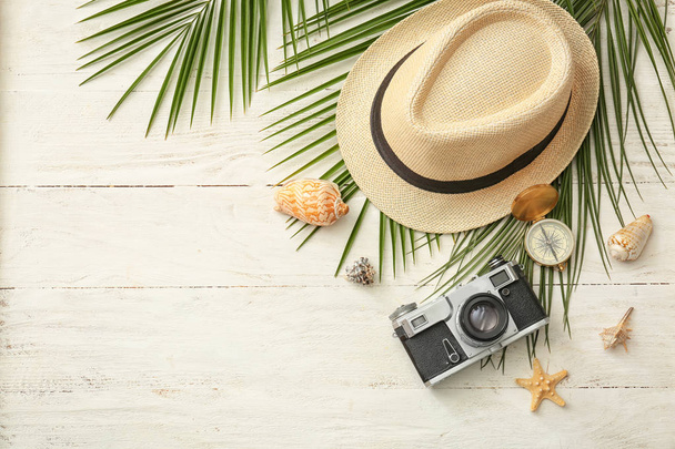 Composición con cámara fotográfica, sombrero y brújula sobre fondo de madera. Vacaciones de verano
 - Foto, imagen