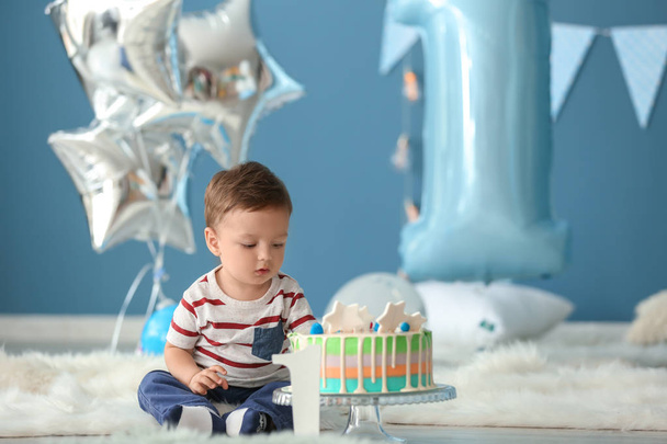 Aranyos kis fiú ül a szobában bolyhos szőnyeg, születésnapi torta - Fotó, kép