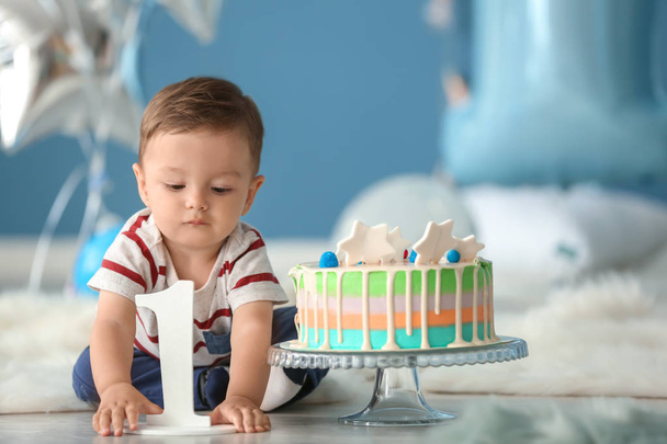 Ładny chłopczyk z tort urodzinowy, siedząc na podłodze w pokojach - Zdjęcie, obraz