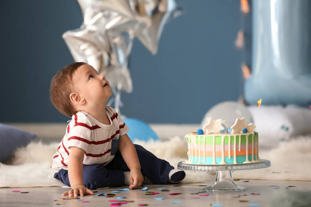 Aranyos kisfiú a padlón szobában ül, születésnapi torta - Fotó, kép