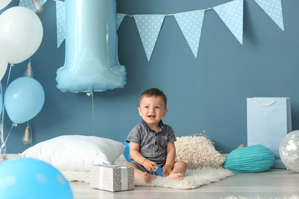 Ładny mały chłopiec siedzi na puszysty dywan w pokoju urządzonego na urodzinowe - Zdjęcie, obraz