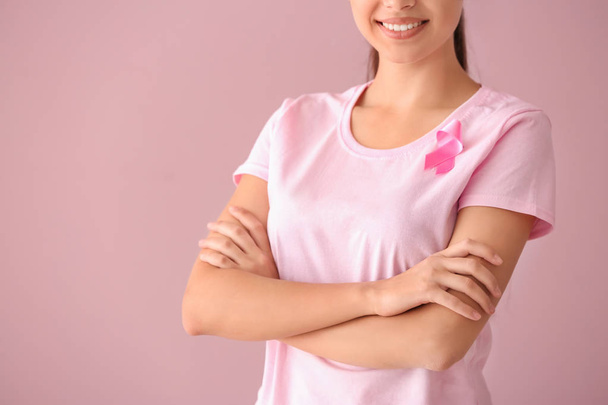 Beautiful woman with pink ribbon on color background. Breast cancer concept - Zdjęcie, obraz