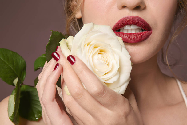 Trendy jonge vrouw met mooie manicure en rose op kleur achtergrond, close-up - Foto, afbeelding