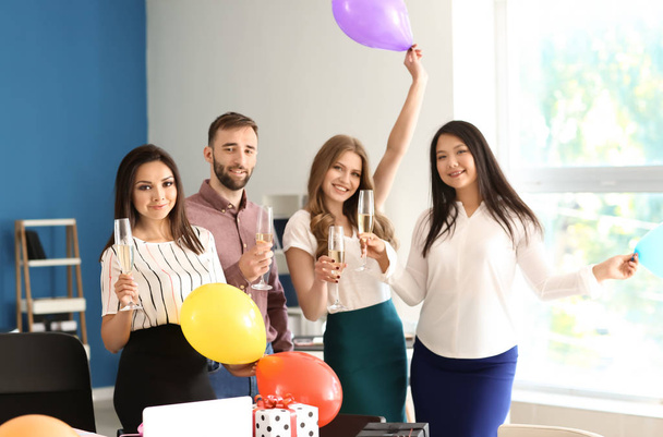 Jóvenes colegas con copas de champán en la fiesta de cumpleaños en la oficina
 - Foto, Imagen