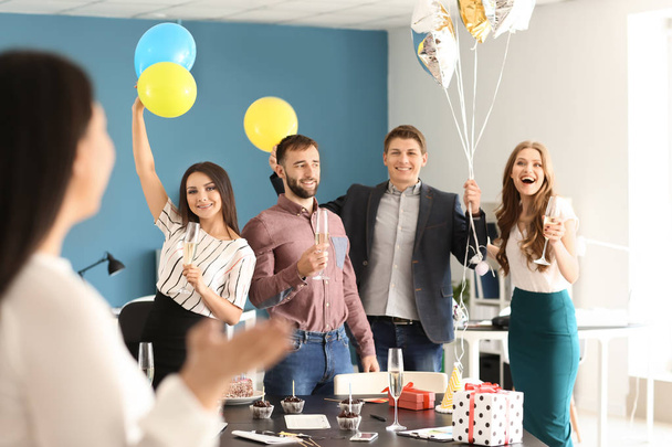 Щасливі колеги на несподіваній вечірці для молодої жінки на її день народження в офісі
 - Фото, зображення