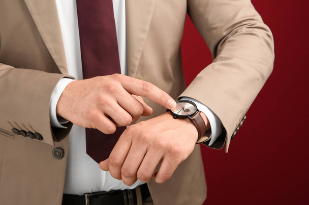 Businessman looking at his watch on color background, closeup. Time management concept - Photo, Image
