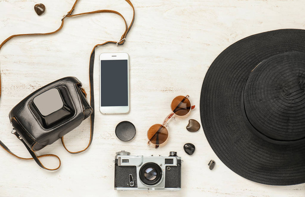Composition  with photo camera, smartphone and hat on white wooden background - Foto, Imagem