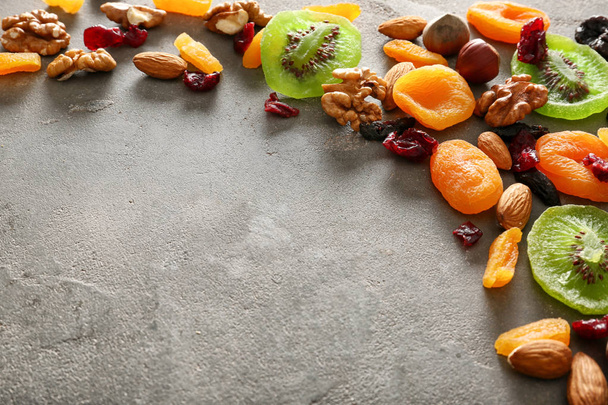 Διάφοροι ξηροί καρποί και αποξηραμένα φρούτα σε γκρι φόντο με υφή - Φωτογραφία, εικόνα