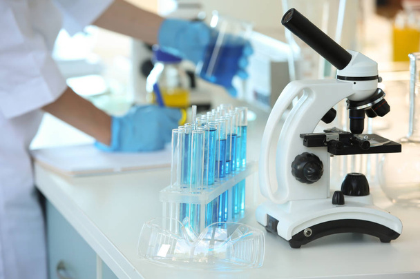 Тестовые трубки с образцами и современным микроскопом на столе в лаборатории
 - Фото, изображение