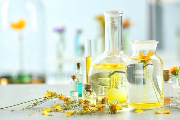 Φαρμακευτικός και εργαστηριακός εξοπλισμός με λουλούδια και νερό στο τραπέζι στο εργαστήριο - Φωτογραφία, εικόνα