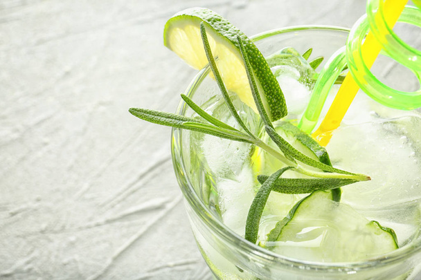 Frisse drank met gesneden komkommer en rozemarijn in glas op tafel, close-up - Foto, afbeelding
