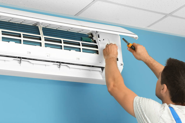 Electricista reparando aire acondicionado en interiores
 - Foto, Imagen