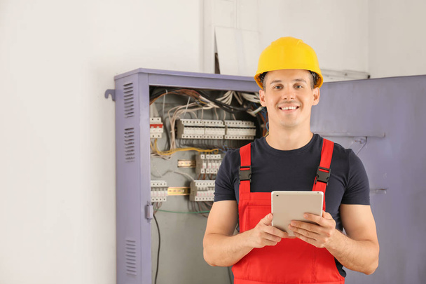 Electrician with tablet PC near distribution board indoors - Photo, Image