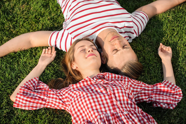 Νεαρό ζευγάρι ξαπλωμένο σε πράσινο γρασίδι σε εξωτερικούς χώρους - Φωτογραφία, εικόνα