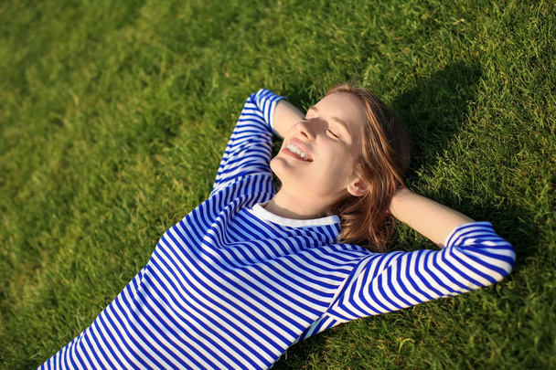 Jeune femme couchée sur l'herbe verte à l'extérieur
 - Photo, image