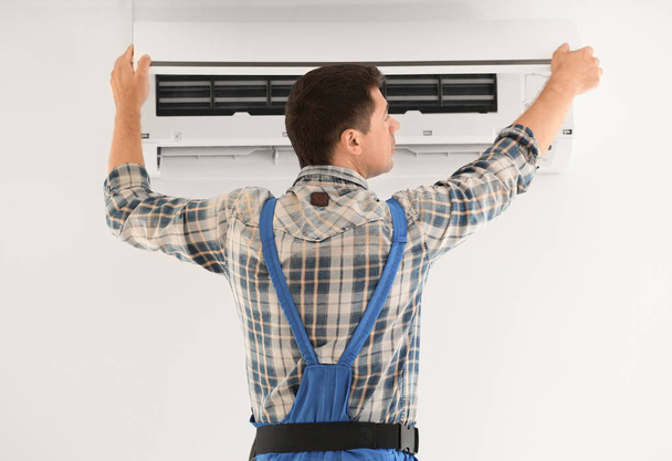 Electricista reparando aire acondicionado en interiores
 - Foto, imagen