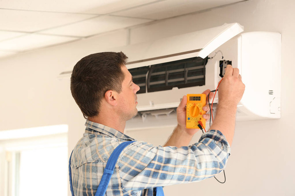 Elektriker misst Spannung der Klimaanlage in Innenräumen - Foto, Bild