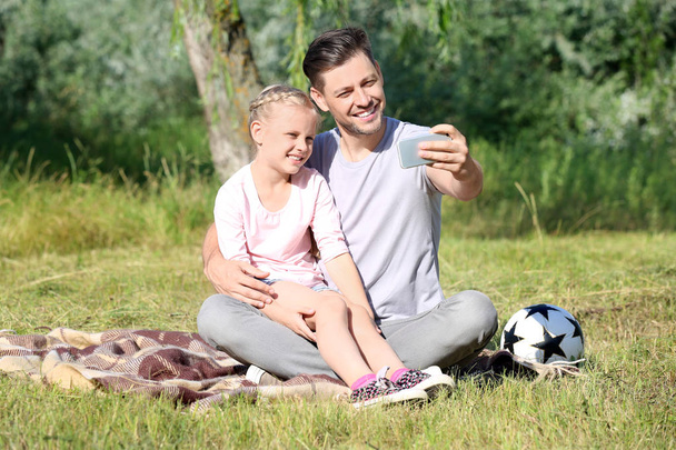Hombre tomando selfie con su pequeña hija en el parque
 - Foto, imagen