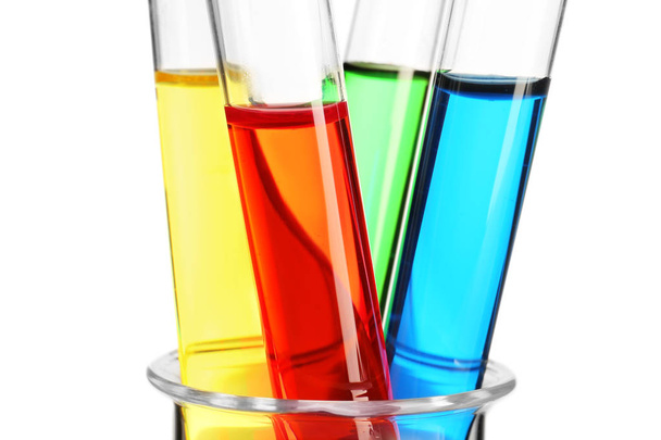 Tubos de ensayo con líquidos de colores en vaso de precipitados de vidrio sobre fondo blanco, primer plano
 - Foto, imagen