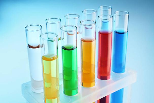 Test tubes with colorful liquids in holder on color background - Foto, imagen