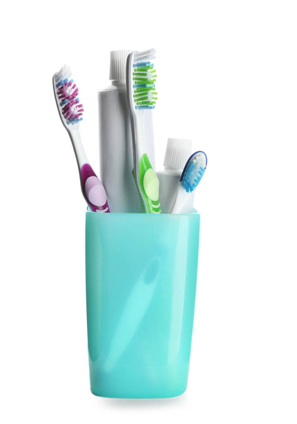 Kuppi hammasharjat ja tahna valkoisella pohjalla
 - Valokuva, kuva