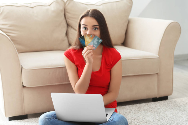 Молодая женщина делает покупки онлайн с кредитными картами и ноутбуком дома
 - Фото, изображение
