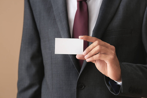 Man with business card on color background, closeup - 写真・画像