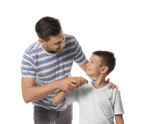 Man teaching his little son how to brush teeth on white background - Foto, afbeelding