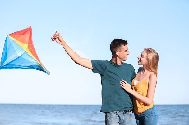 Young couple flying kite near sea - Fotó, kép