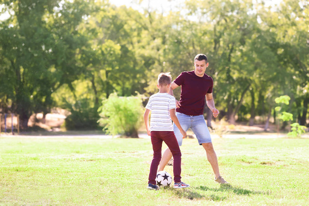 Petit garçon avec son père jouant au football en plein air
 - Photo, image