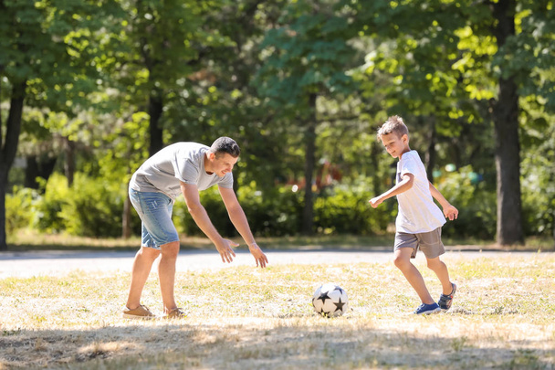 Little boy with his dad playing football outdoors - Фото, зображення