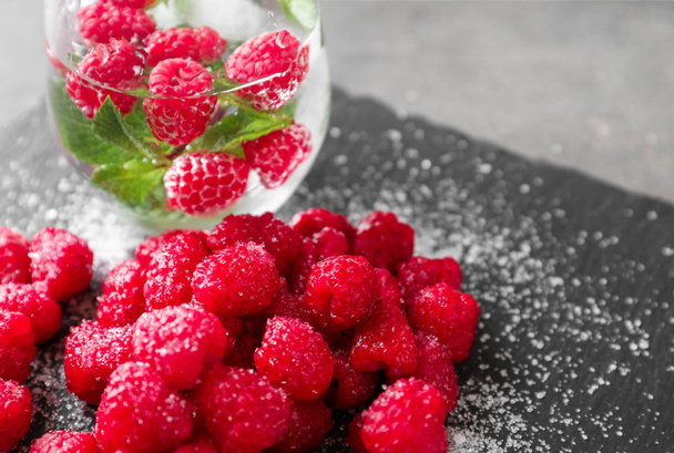 Delicious fresh ripe raspberries with sugar and cold drink on slate plate - Foto, imagen