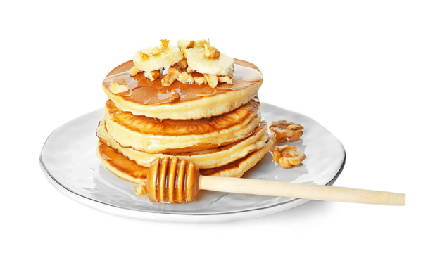 Piatto con gustosi pancake, noci e banana affettata su sfondo bianco
 - Foto, immagini