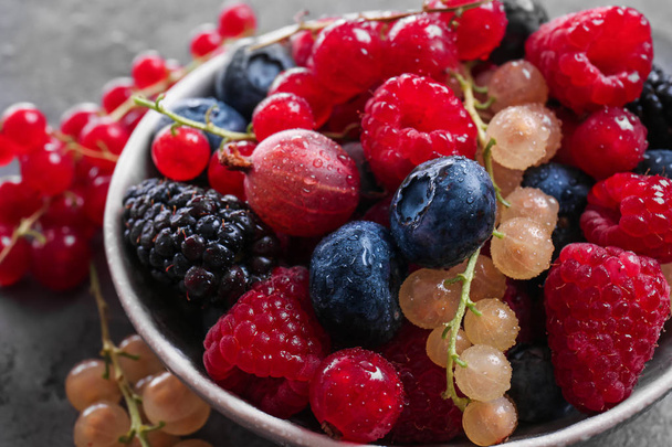 Bowl with different ripe berries on table, closeup - Foto, Bild